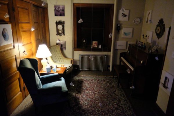 A wide view of the installation, including sentimental objects and glass bottles hanging from the ceiling.