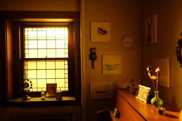 A wide view of the installation, including sentimental objects and glass bottles hanging from the ceiling.