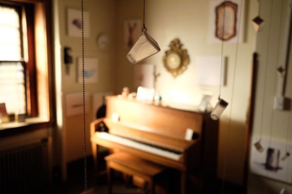 A wide view of the installation, including sentimental objects and glass bottles hanging from the ceiling.