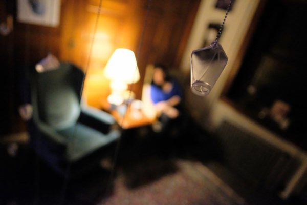 A wide view of the installation, including sentimental objects and glass bottles hanging from the ceiling.