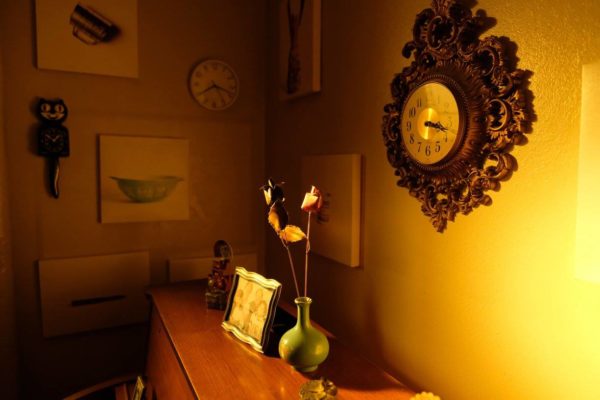 Framed photographs and flowers in a vase on top of a piano.