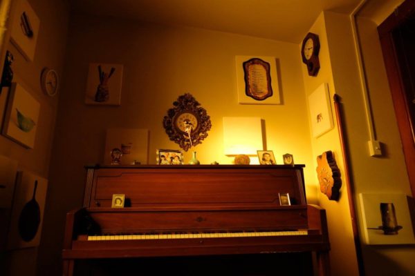 A wide view of the installation, including sentimental objects and glass bottles hanging from the ceiling.