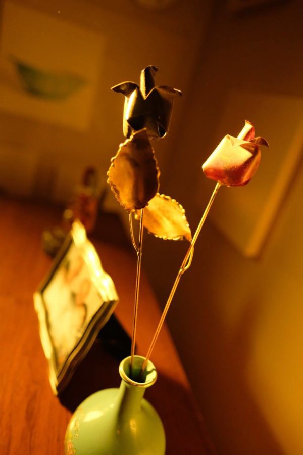 Framed photographs and flowers in a vase on top of a piano.