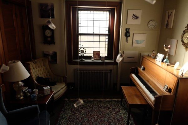 A wide view of the installation, including sentimental objects and glass bottles hanging from the ceiling.