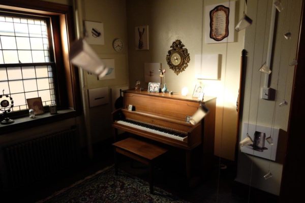 A wide view of the installation, including sentimental objects and glass bottles hanging from the ceiling.