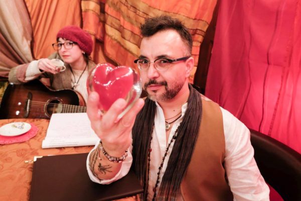 A person holding up a red glass heart.