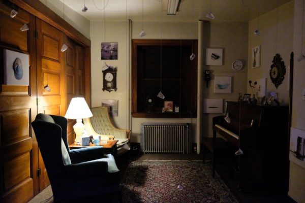 A wide view of the installation, including sentimental objects and glass bottles hanging from the ceiling.