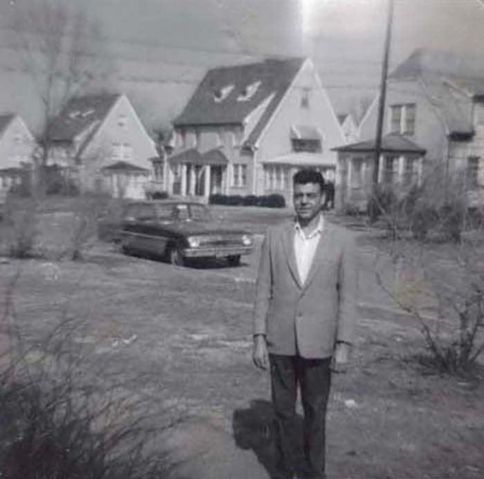 James A. Sampson Sr. standing outside in front of houses.