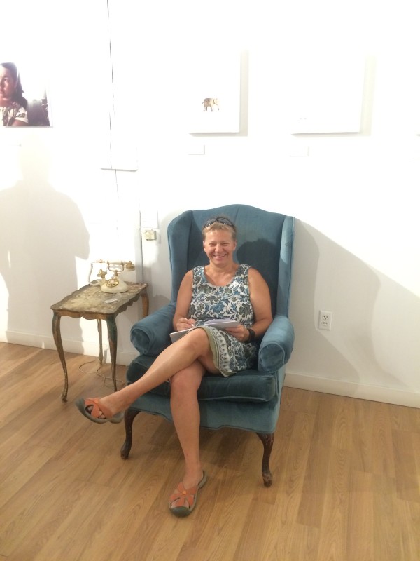 A woman sitting in an antique armchair in the installation.
