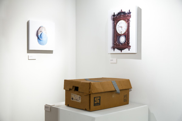 A cardboard box on a pedestal and a photo of an old wall clock.