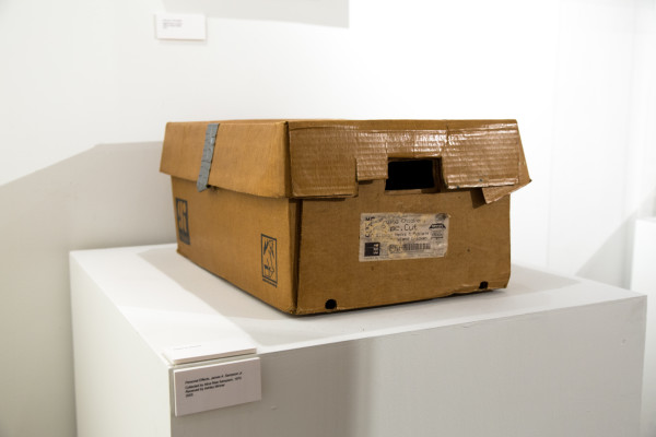 A cardboard box on a pedestal and a photo of an old wall clock.