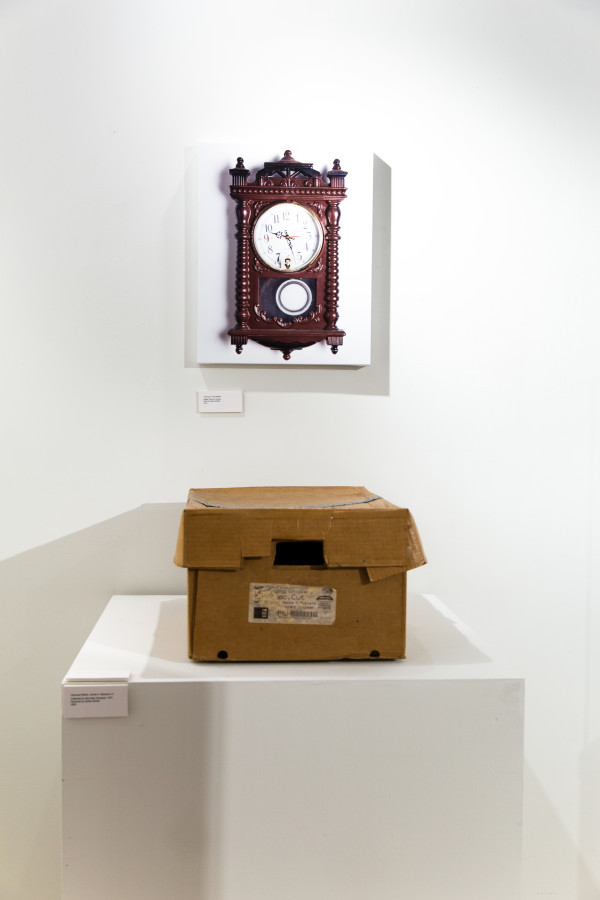 A cardboard box on a pedestal and a photo of an old wall clock.
