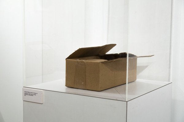 A cardboard box on a pedestal and a photo of an old wall clock.