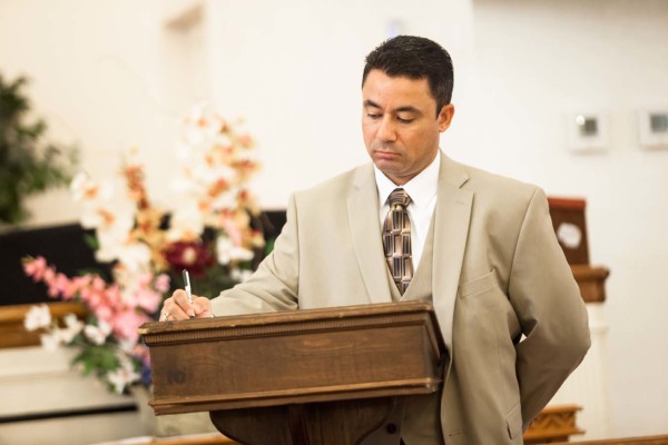 A man standing at a podium, writing.