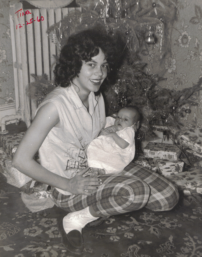 Jeanette Locklear Walker holding a baby in front of a Christmas tree and presents.