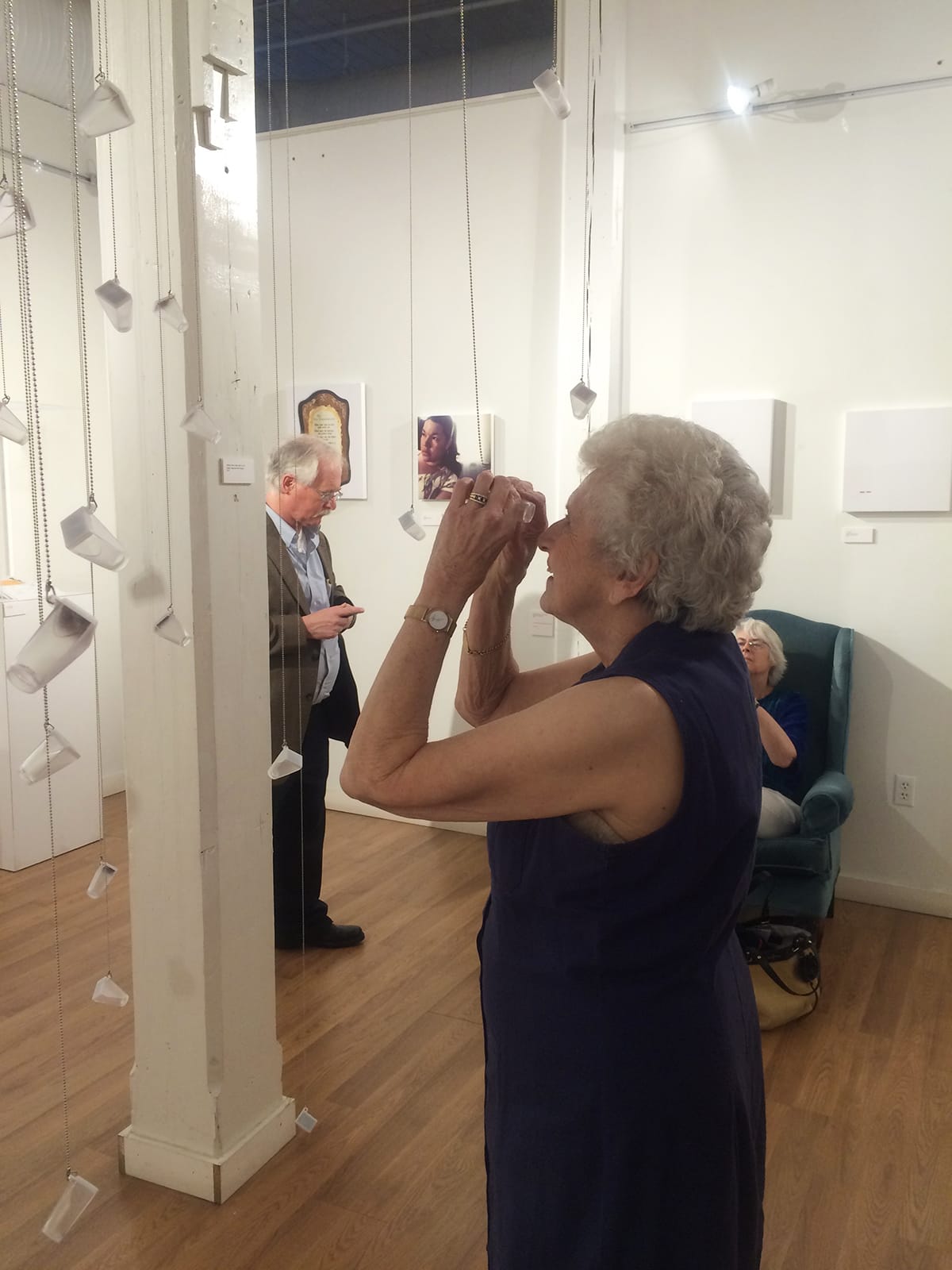 A woman looking through a glass bottle in the installation.
