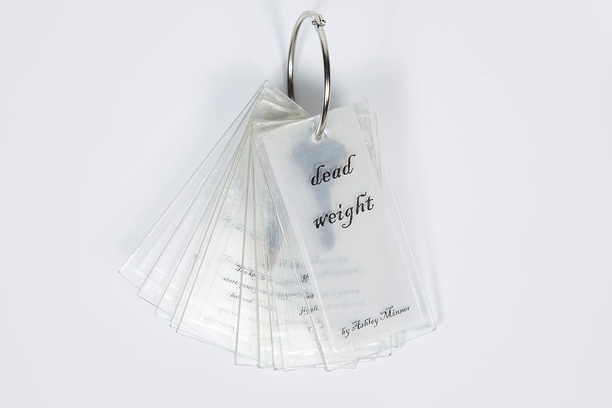 The cover of Dead Weight, a book made from plastic film strips on a keychain.